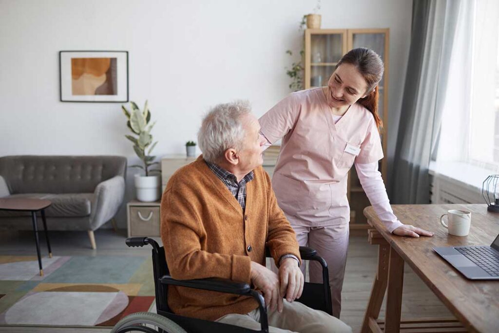 A group of older adults smiling and participating in a gentle group exercise class indoors.