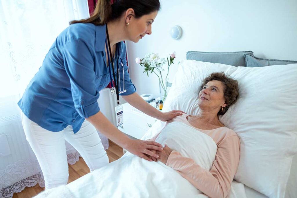 Older resident speaks with an interviewer in a bright assisted living common room beside a table and tea. KEYWORDS: ["assisted living resident interview", "senior daily routine", "assisted living common room"]